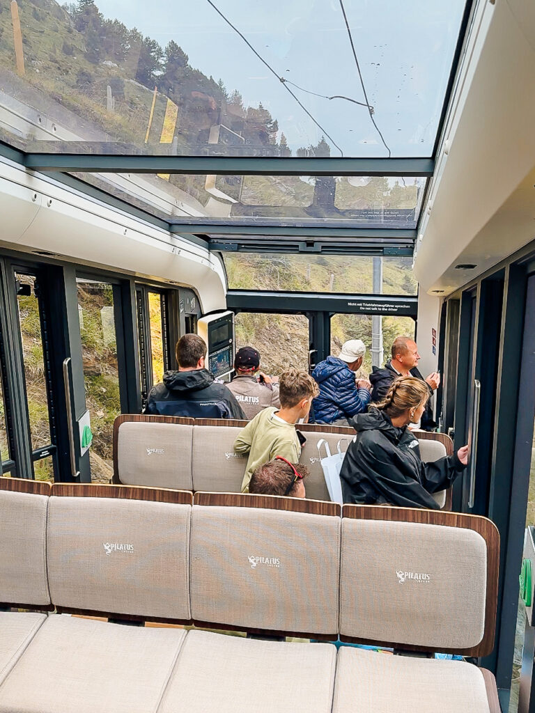 Passengers seated in the modern cogwheel train with wide windows and panoramic views up Mount Pilatus.